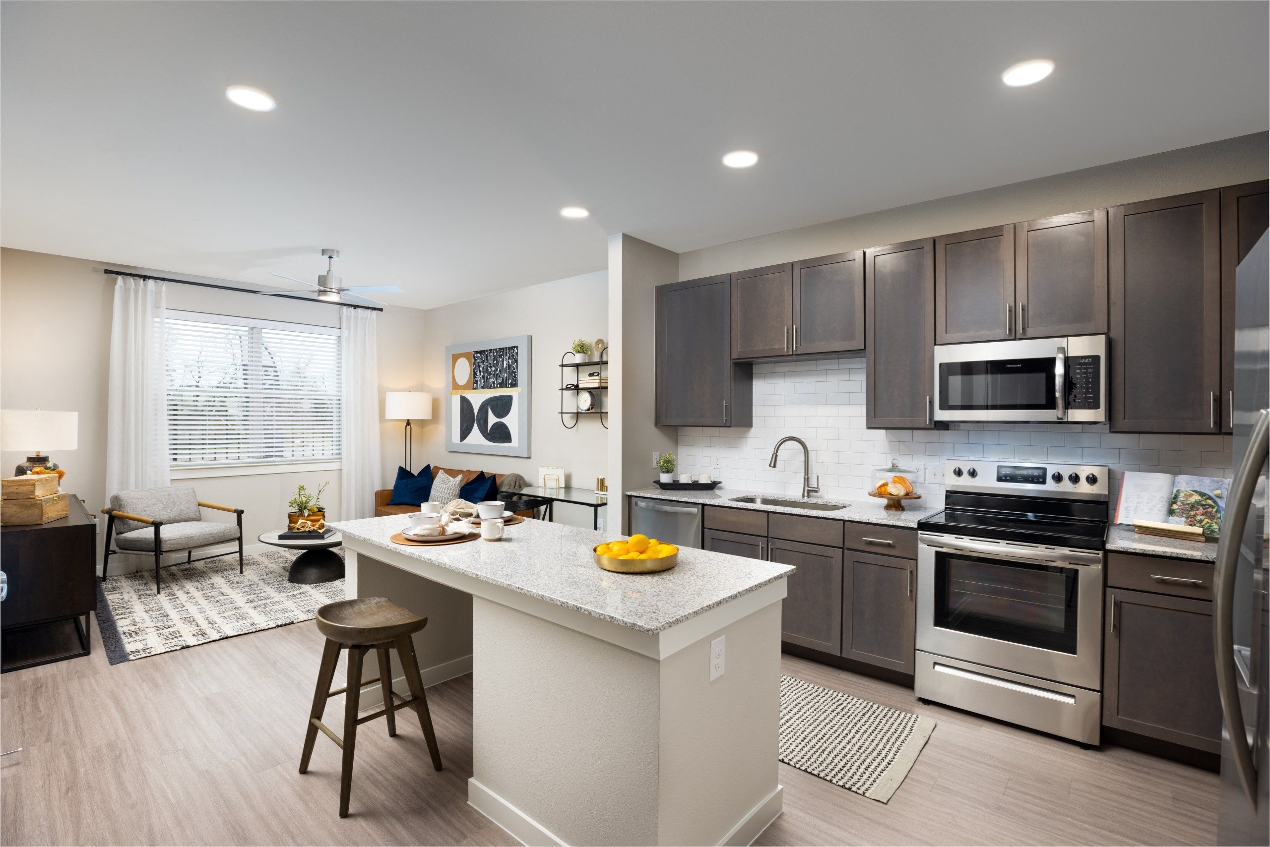 an open kitchen and living room with a large island and stainless steel appliances